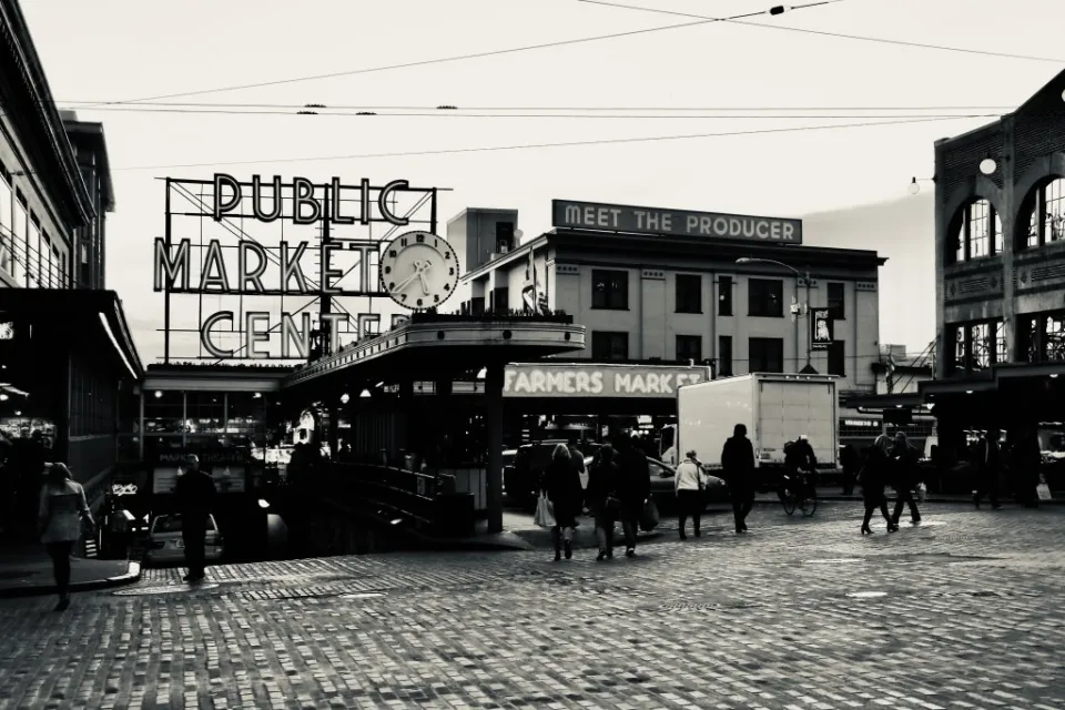 Black and white photo of Pike Place Market entrance in Seattle with "PUBLIC MARKET" and "Meet the producer" signs